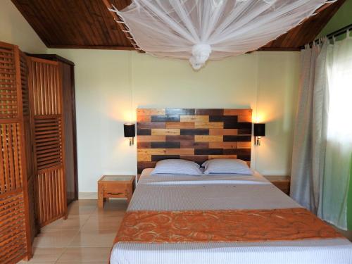 a bedroom with a bed with a wooden headboard at hotel trecicogne in Morondava