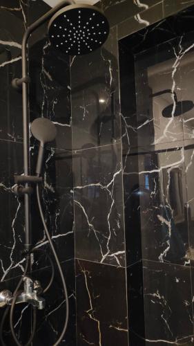 a shower with a black and white marble wall at Apartament u Danusi in Złoty Stok