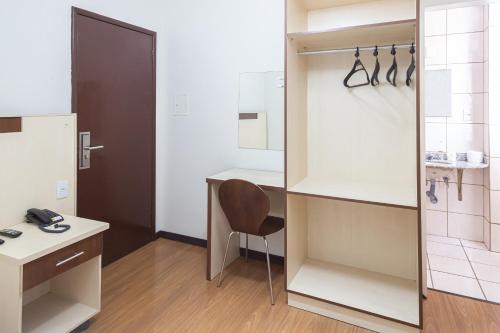 a room with a desk and a chair and a mirror at Hotel Gracher Brusque in Brusque