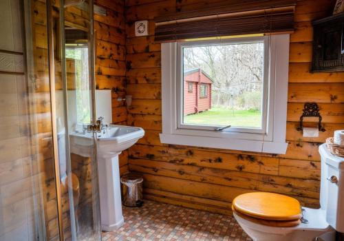 een badkamer met een wastafel, een toilet en een raam bij Scalpay Lodge in Duirinish