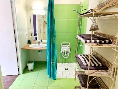 a green bathroom with a sink and towels at Le Domaine de Kerlys in Briec