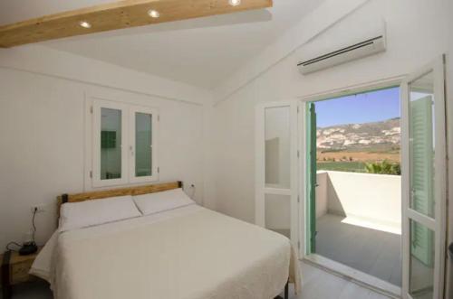 Habitación blanca con cama y ventana en Villa degli Alberi, en Buseto Palizzolo