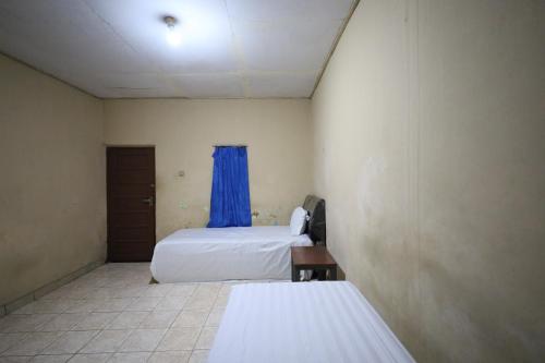 a room with two beds and a blue curtain at SPOT ON 92390 Wilma Kost Syariah in Banjarmasin