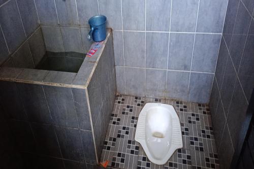 ein Bad mit einem Urinal in einer gefliesten Kabine in der Unterkunft SPOT ON 92390 Wilma Kost Syariah in Banjarmasin