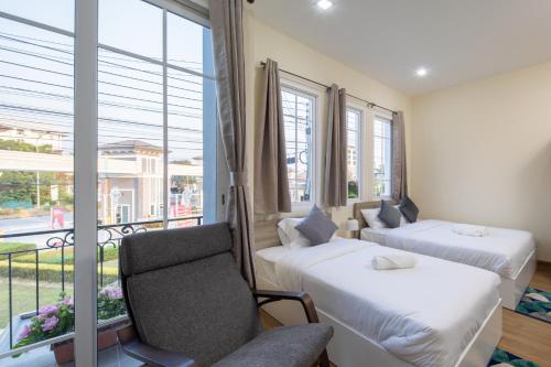 a room with two beds and a chair and a window at 46 Golden House in Chiang Mai