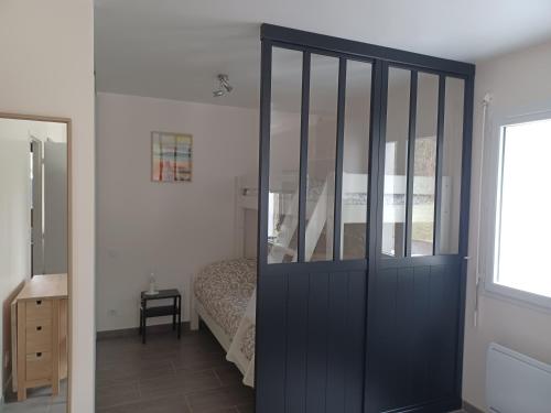 1 dormitorio con una puerta corredera azul y 1 cama en Appartement Havre de paix Landais en Saint-Barthélemy