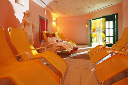 a waiting room with orange chairs and a mannequin at Radenci Spa Resort - Sava Hotels & Resorts in Radenci