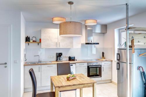 cocina con armarios blancos y mesa de madera en Ferienwohnung Am Rehgarten, en Ramsen