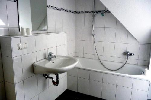 La salle de bains est pourvue de carrelage blanc, d'un lavabo et d'une douche. dans l'établissement Apartment-Sonnenparadies-Wandlitz, à Wandlitz