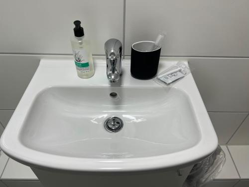 un fregadero blanco con cepillo de dientes y una botella de pasta de dientes en Ullis Pension für Monteure & Handwerker, en Malsch