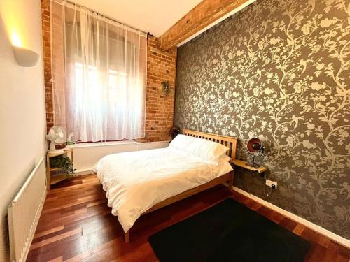 a bedroom with a bed and a wall with floral wallpaper at Charming 2 Bed Apartment in Centre of Nottingham in Nottingham