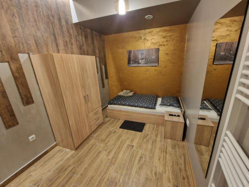 a small room with a bed and wooden cabinets at Apartmani New York in Nova Gradiška