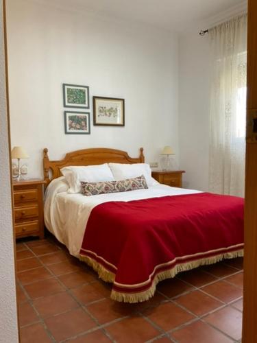 een slaapkamer met een bed met een rode deken bij El secanillo in San Roque