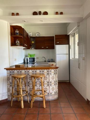 uma cozinha com um balcão com bancos e um frigorífico em El secanillo em San Roque