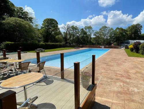 a pool with a wooden deck and a table and chairs at SNOWDONIA COTTAGE Glan Gwna Holiday Park in Caernarfon