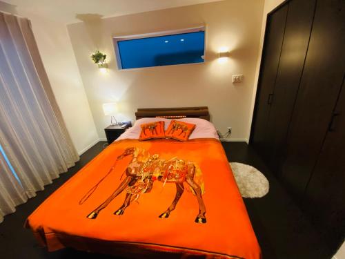a bedroom with a bed with an orange comforter at Love House in Osaka