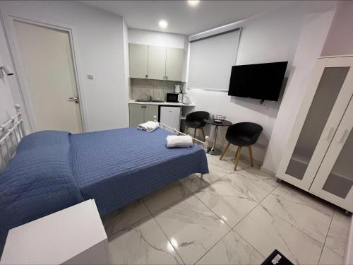a bedroom with a blue bed and a kitchen at Jacks Apartment in Paphos City