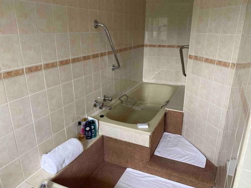 a bathroom with a tub and a sink with towels at Great Pulteney St. Maisonette (parking) in Bath