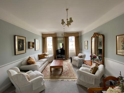a living room with white furniture and a mirror at Great Pulteney St. Maisonette (parking) in Bath