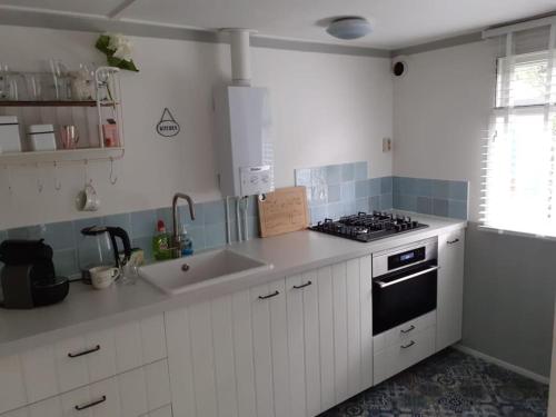 a kitchen with white cabinets and a stove top oven at Knus buitenhuisje aan de Veluwe in Putten