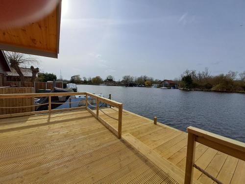 a wooden dock with a boat on the water at Nature's Nook - Norfolk Broads in Brundall