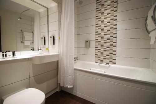 a bathroom with a sink and a tub and a toilet at Silurian Hotel Newport in Newport