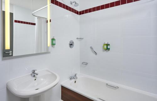 La salle de bains blanche est pourvue d'un lavabo et d'une baignoire. dans l'établissement Leonardo Hotel Milton Keynes, à Milton Keynes