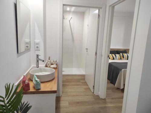1 dormitorio y baño blanco con lavabo. en Apartamentos turísticos Demar en O Grove