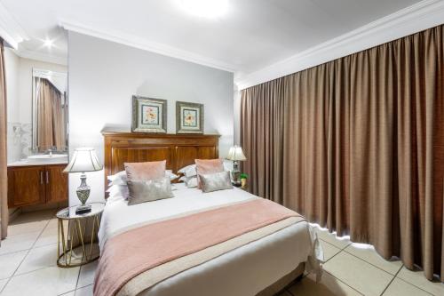 a bedroom with a large bed and curtains at Adato Guesthouse in Potchefstroom