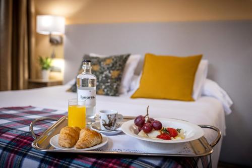 a tray with food and a bottle of orange juice and fruit at Hotel Monasterio Benedictino in Calatayud