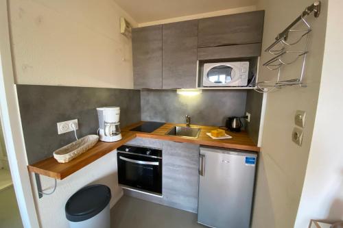 une petite cuisine avec un évier et un micro-ondes dans l'établissement 23m paisible avec balcon près de la plage !, à Cabourg