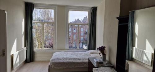 a bedroom with a bed and two large windows at Frank’s and Chong’s excellent location in Amsterdam