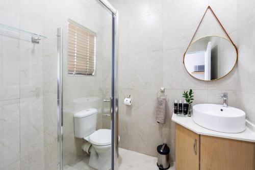 a bathroom with a toilet and a sink and a mirror at Adato Guesthouse in Potchefstroom