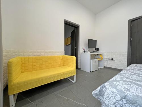 a yellow couch in a room with a bed at Apollo Rooms by Albert's Apartment in Larnaka
