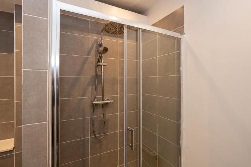 a shower with a shower head in a bathroom at Pillo Rooms - Spacious 4 Bedroom Detached House close to Heaton Park in Manchester