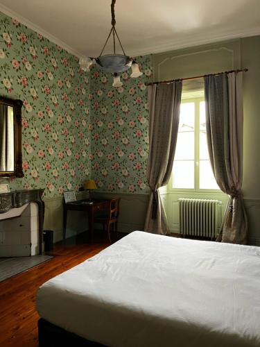 a bedroom with a white bed and floral wallpaper at Hôtel Restaurant Chez Gervais in Quingey