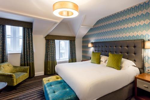 a bedroom with a large bed and a chair at Inn on the Square in Keswick