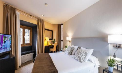 a bedroom with a white bed and a television at Hotel Monasterio Benedictino in Calatayud