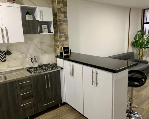 Una cocina con gabinetes blancos y una encimera negra. en Aparta_Suite_Sogamoso, en Sogamoso
