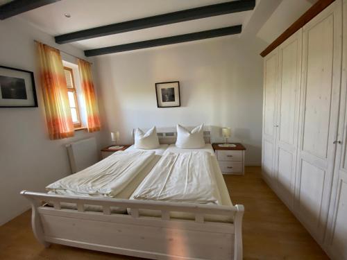 um quarto com uma cama com lençóis brancos e almofadas em Bummert Am Hafen 1 em Krummhörn