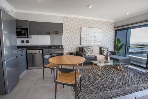 een keuken en een woonkamer met een tafel en een bank bij The Space To Be in Durban