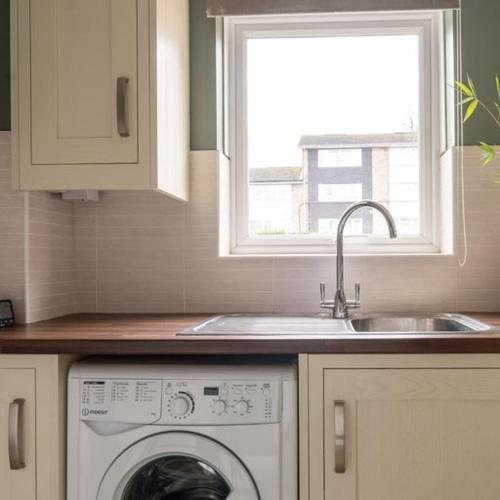 a kitchen with a sink and a washing machine at The Bracken's by Ritual Stays in Hemel Hempstead