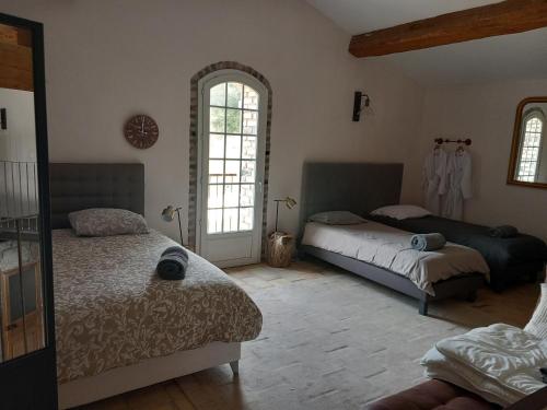 um quarto com 2 camas e 2 janelas em Mas du dragon - 8 personnes- Jacuzzi Piscine chaufée em Saint Jean du Pin