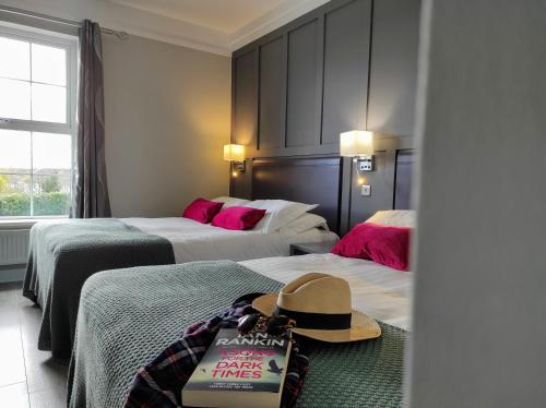 a hotel room with two beds and a hat on the floor at Kilkenny House Boutique Hotel in Kilkenny