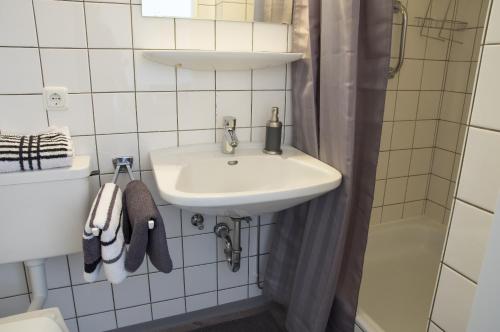 ein weißes Bad mit einem Waschbecken und einer Dusche in der Unterkunft Apartmenthaus Frauenpreis FeWo 61 in Cuxhaven