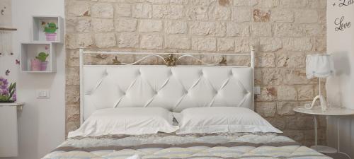 B&B Oceano في مونوبولي: سرير أبيض مع وسائد بيضاء وجدار من الطوب