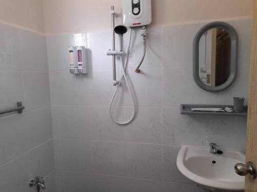 baño blanco con ducha y lavamanos en Margereth Cottage, en Kuala Penyu