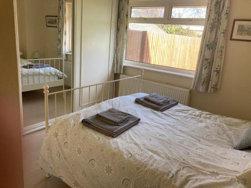 a bedroom with a bed with two towels on it at bungalow on the south coast & new forest in Lymington