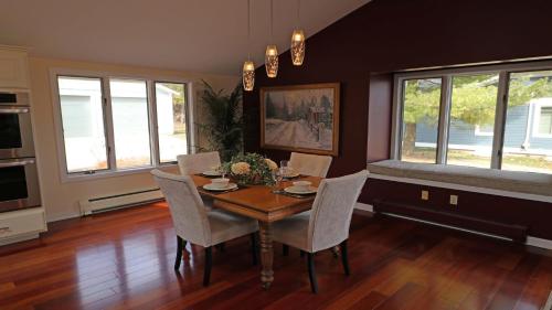 a dining room with a table and chairs and windows at Harbor Bluff in Harbor Springs