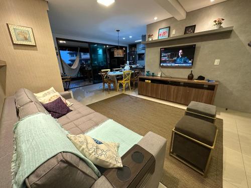 ein Wohnzimmer mit einem Sofa und einem TV in der Unterkunft RIVIERA MANHATTAN - Luxuoso 4 quartos, varanda Gourmet in Aquiraz